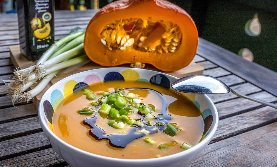 Pumpkin soup garnished with green onions and drizzled with pumpkin seed oil.