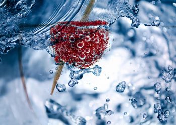 Strawberry with bubbles submerged in water.