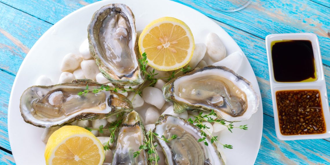 Oysters served on a plate with lemon wedges and dipping sauces.