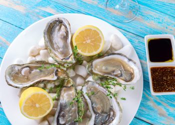 Oysters served on a plate with lemon wedges and dipping sauces.
