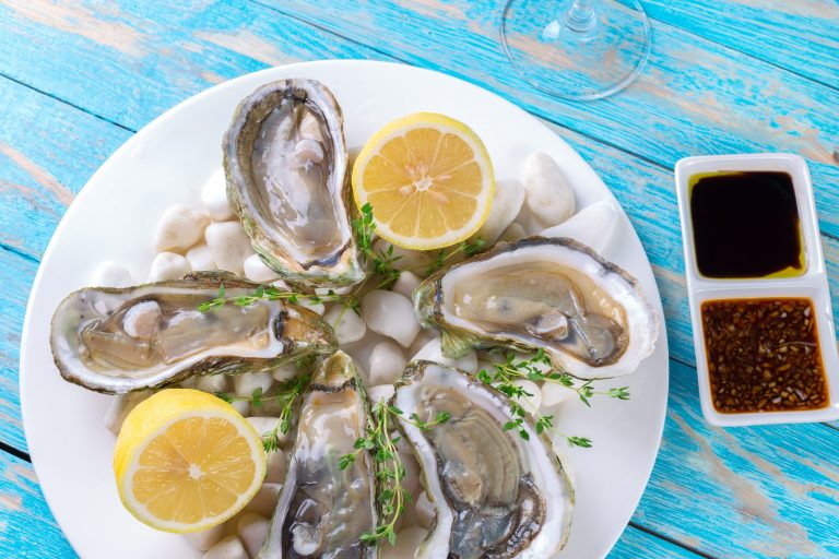 Oysters served on a plate with lemon wedges and dipping sauces.
