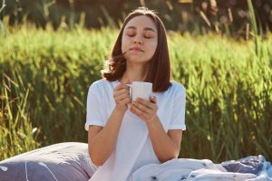 Woman enjoying a warm drink outdoors in nature.