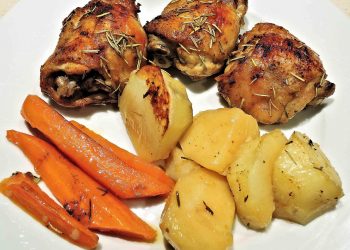 Roasted chicken with rosemary, potatoes, and carrots on a plate.