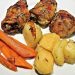 Roasted chicken with rosemary, potatoes, and carrots on a plate.