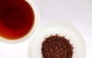 Brewed rooibos tea with loose leaves on a plate.