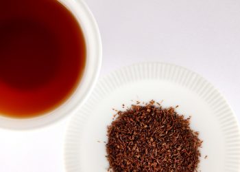 Brewed rooibos tea with loose leaves on a plate.