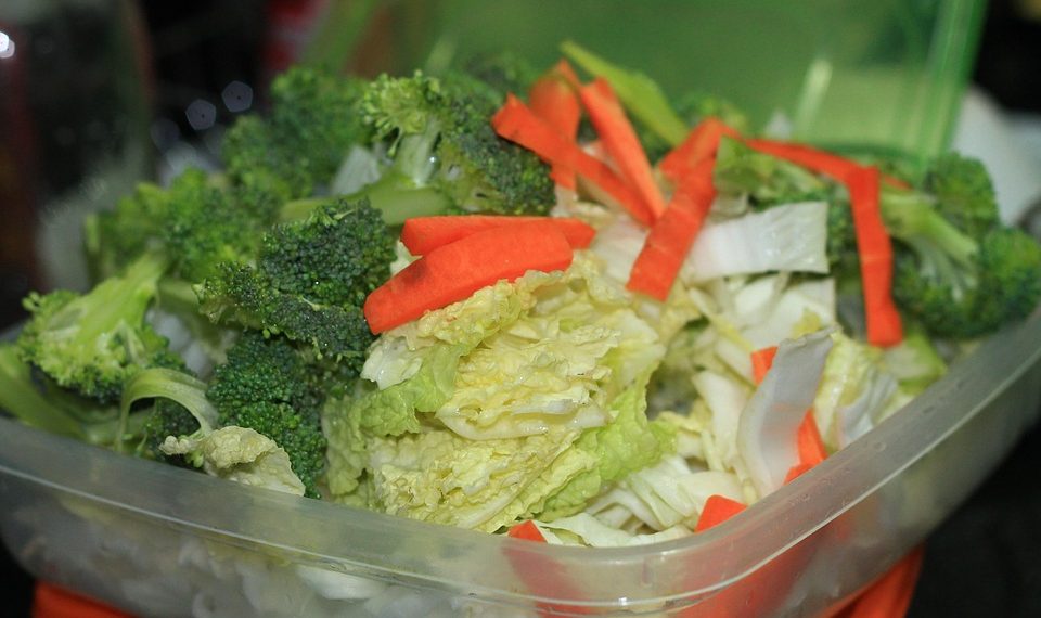 Fresh mixed vegetables in a container, including broccoli, carrots, and cabbage.