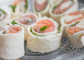 Salmon tortilla rolls with fresh greens on a plate.