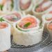 Salmon tortilla rolls with fresh greens on a plate.