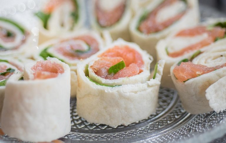 Salmon tortilla rolls with fresh greens on a plate.