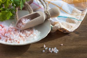Pink Himalayan salt in wooden scoop on the table.