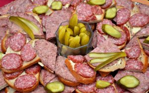 Open sandwiches with salami and pickles arranged on a platter.