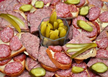 Open sandwiches with salami and pickles arranged on a platter.