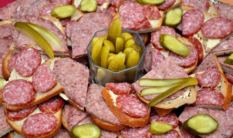 Open sandwiches with salami and pickles arranged on a platter.