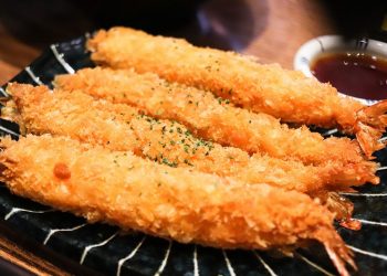 Crispy tempura shrimp with dipping sauce on a plate.