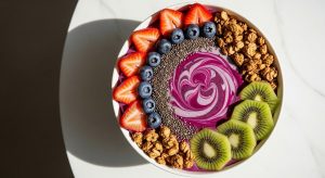 Berry smoothie bowl with kiwi, strawberries, blueberries, granola, and chia seeds.