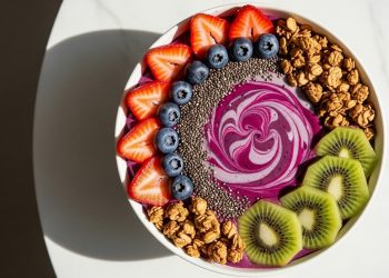 Berry smoothie bowl with kiwi, strawberries, blueberries, granola, and chia seeds.