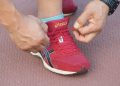 Tying red running shoe laces tightly on track.