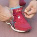 Tying red running shoe laces tightly on track.
