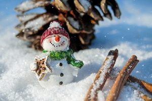 Snowman figurine with gingerbread in snowy setting.