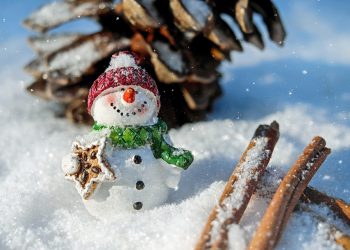 Snowman figurine with gingerbread in snowy setting.