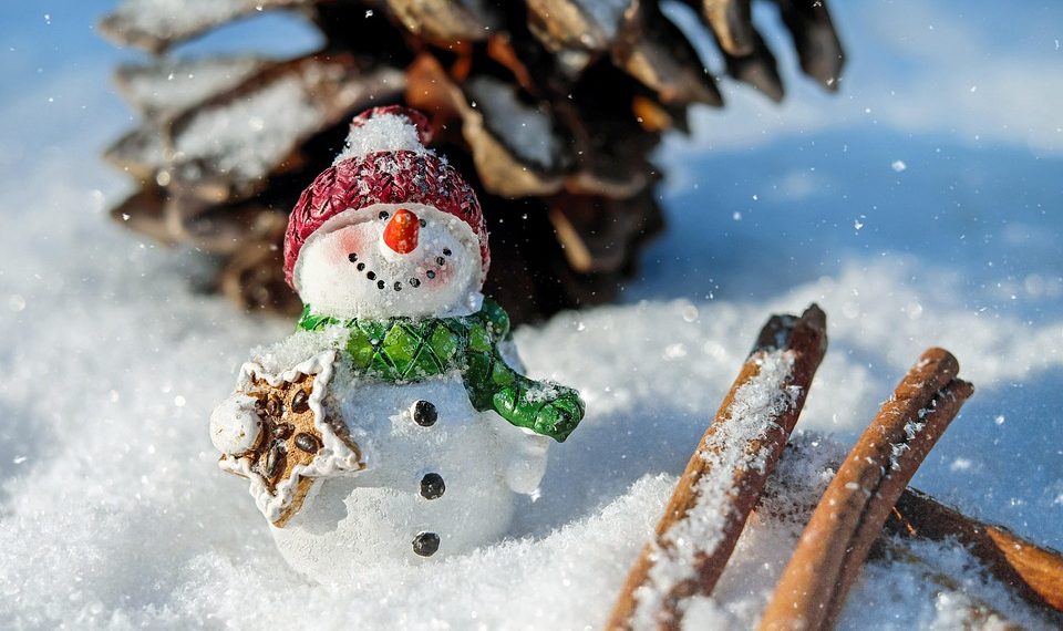 Snowman figurine with gingerbread in snowy setting.