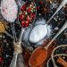 Various spices on spoons, including salt, pepper, mustard, and paprika.