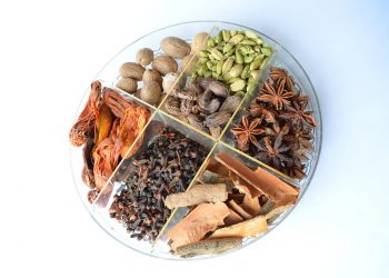 Assorted spices neatly arranged in a round tray.