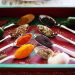 Spoons filled with colorful spices and herbs on a red tray.