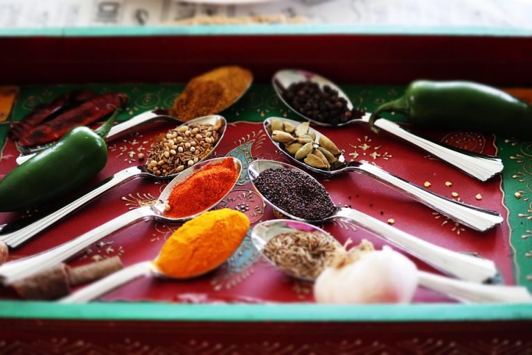 Spoons filled with colorful spices and herbs on a red tray.
