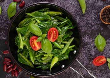 Stir-fried greens with tomatoes and basil in a pan.