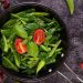 Stir-fried greens with tomatoes and basil in a pan.
