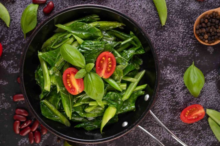 Stir-fried greens with tomatoes and basil in a pan.
