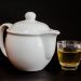 White teapot with a glass cup of herbal tea.