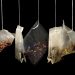 Mixed herbal tea bags hanging against a dark background.