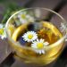 Chamomile flowers floating in a cup of herbal tea.