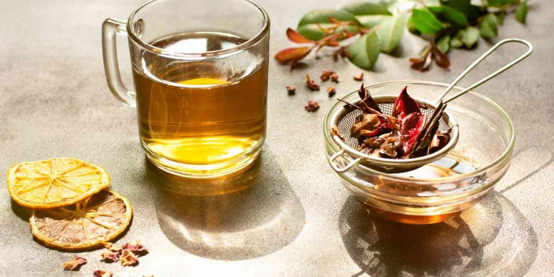 Warm herbal tea with dried citrus slices and spice strainer.
