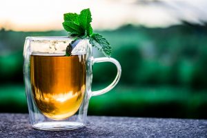 Tea with mint leaves in a clear glass on an outdoor table.