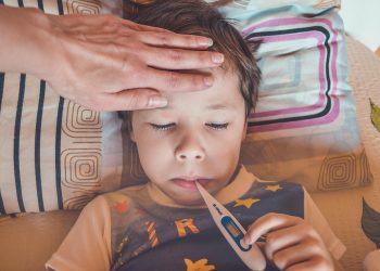 Child with fever checking temperature with a thermometer.