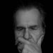 Elderly man deep in thought, contemplating in darkness.