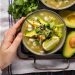 Green pozole with avocado and lime, garnished with cilantro.