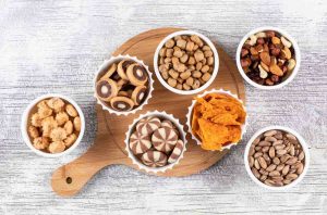 Assorted snacks in bowls on a wooden board.