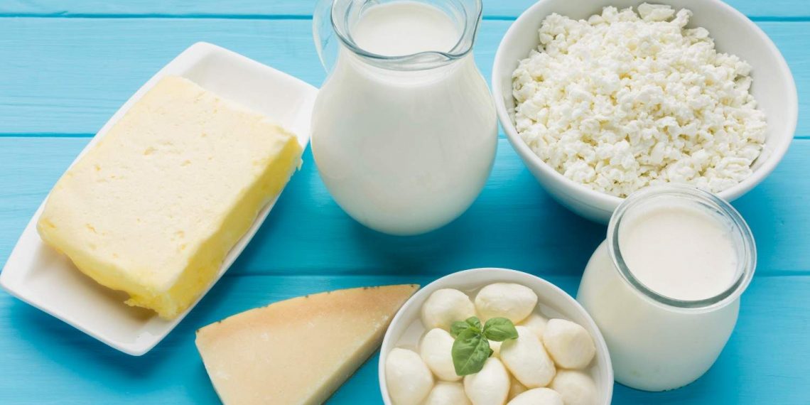 Various dairy products on a blue table, including milk, cheese, and cottage cheese.