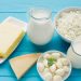 Various dairy products on a blue table, including milk, cheese, and cottage cheese.