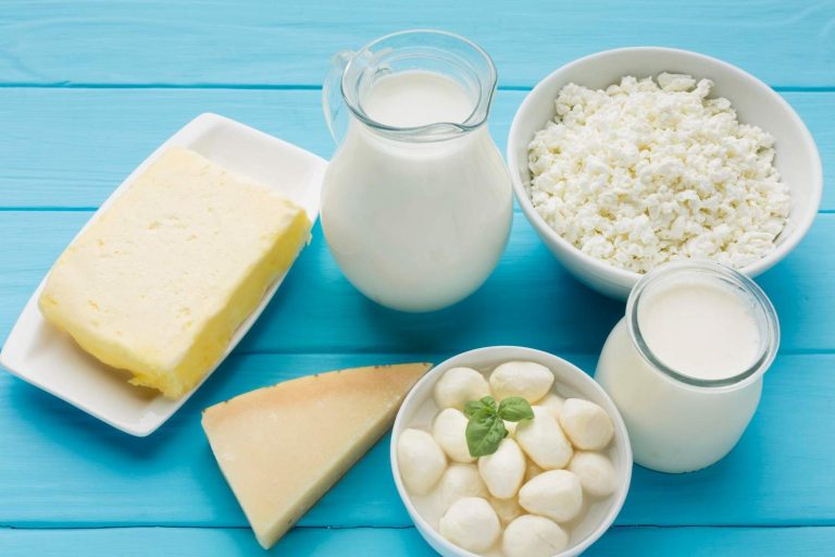 Various dairy products on a blue table, including milk, cheese, and cottage cheese.