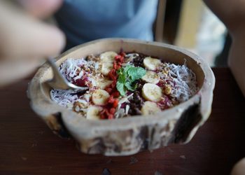 Smoothie bowl topped with bananas, berries, and mint.