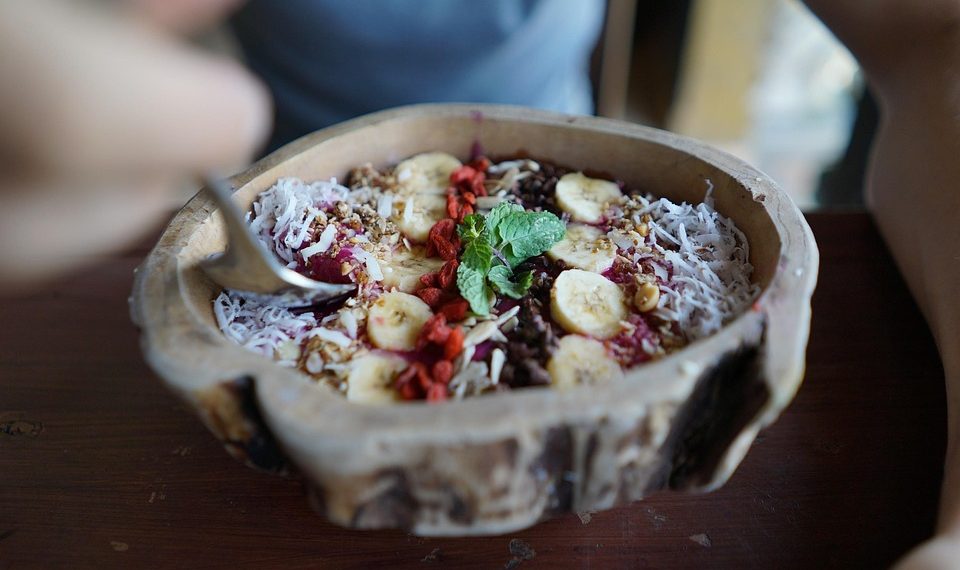 Smoothie bowl topped with bananas, berries, and mint.