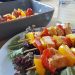 Grilled chicken skewers with bell peppers on a bed of fresh lettuce.