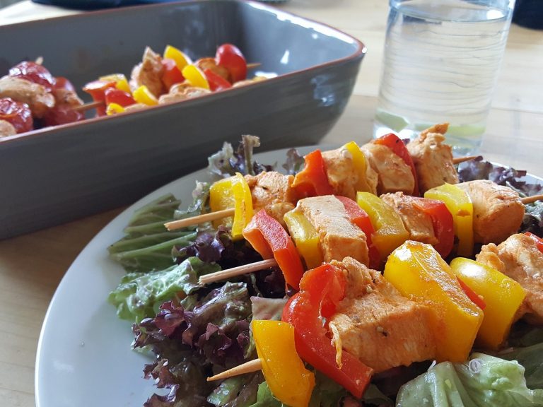Grilled chicken skewers with bell peppers on a bed of fresh lettuce.