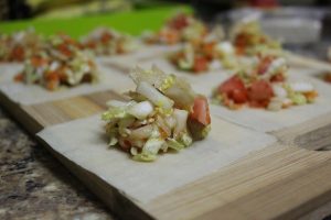 Fresh vegetable filling on dumpling wrappers.
